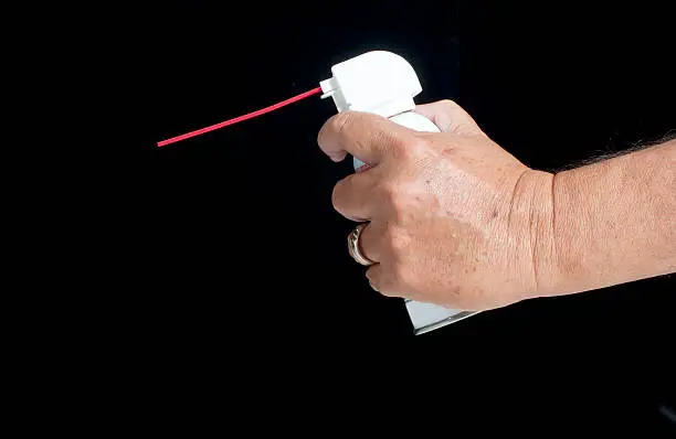 Male hand holding compressed gas duster against a black background