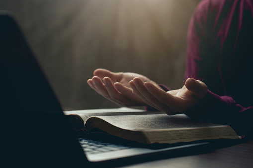 Hands together in prayer for god blessing to wish to have a better life. man hands praying to god with the bible on his laptop. believe in goodness. spirituality and religion, and bible prayer online