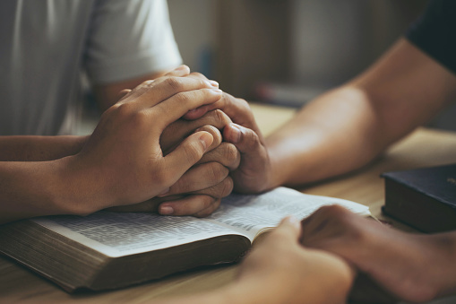 Christian group of people Holding hands together and praying on the holy bible. devotional for prayer meeting concept. praying worship to believe. Encouraging each other to get through the crisis.Love