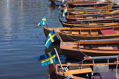 Wooden boats with swedish flags in the harbor of Valdemarsvik on the Baltic Sea coast of Sweden.