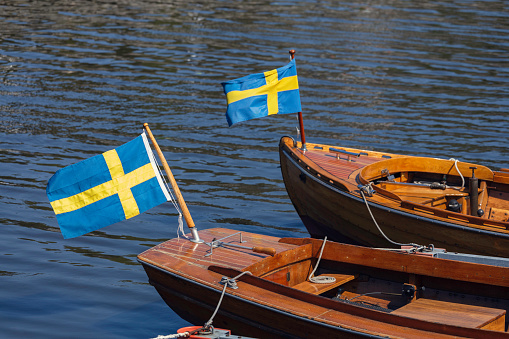 Wooden boats with swedish flags on the Baltic Sea coast of Sweden.
