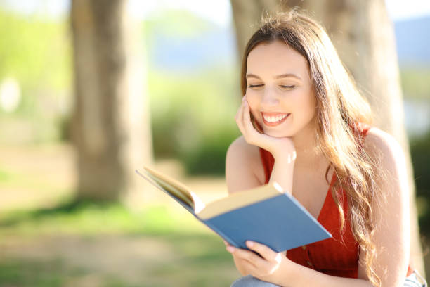 istock Happy reader reading a paper book in nature 1530231390