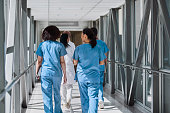 Rear view of female nurses walking with coworkers in hospital corridor