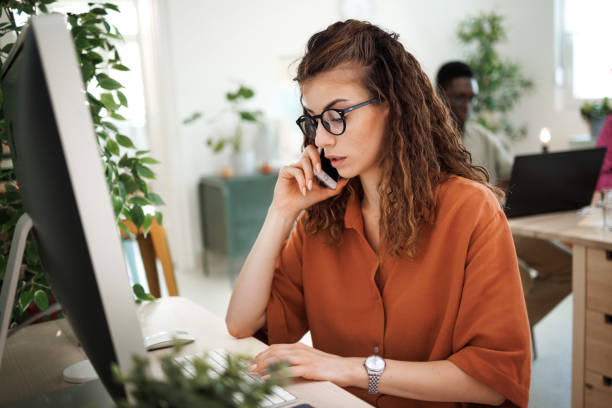 istock Young causally clothed woman talking on a mobile phone while working at office 1530249229