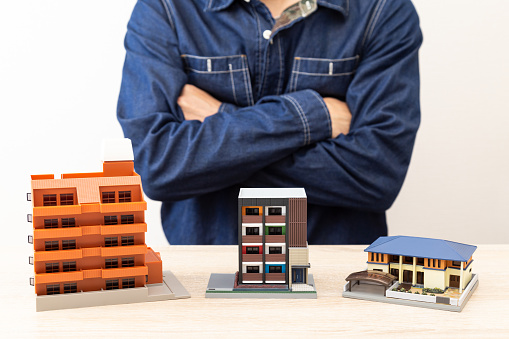 Man folding his arms in front of a house model