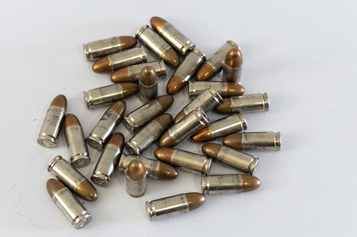 Pile of golden 9mm pistol bullets on a white background