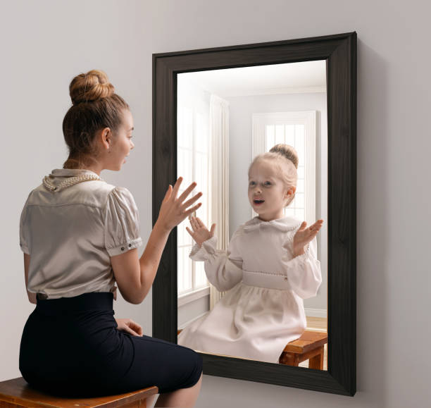 istock Creative conceptual collage. Excited young girl looking in mirror and seeing reflection of little girl, her child self 1530315733