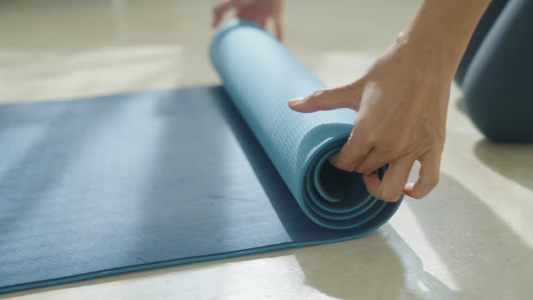 Hand of asian woman mat yoga apart rolling up and preparing to doing yoga class