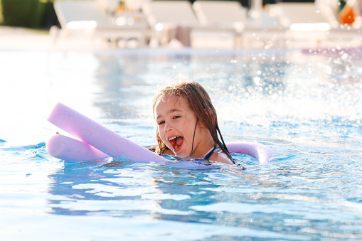 Mother with two daughters having fun in indoor swimming-pool. Girl is resting at the water park. Active happy kid. Swimming school for small children. Concept friendly family sport summer vacation.