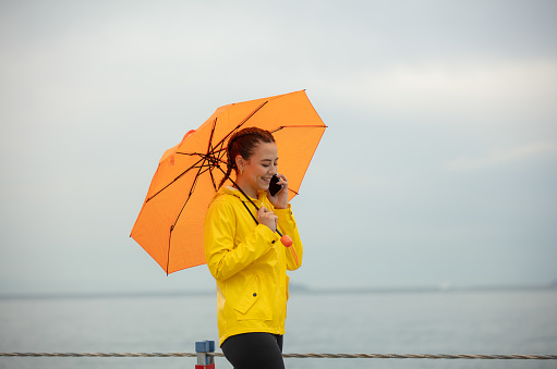 Young woman is walking on the Coastline in rainy day.