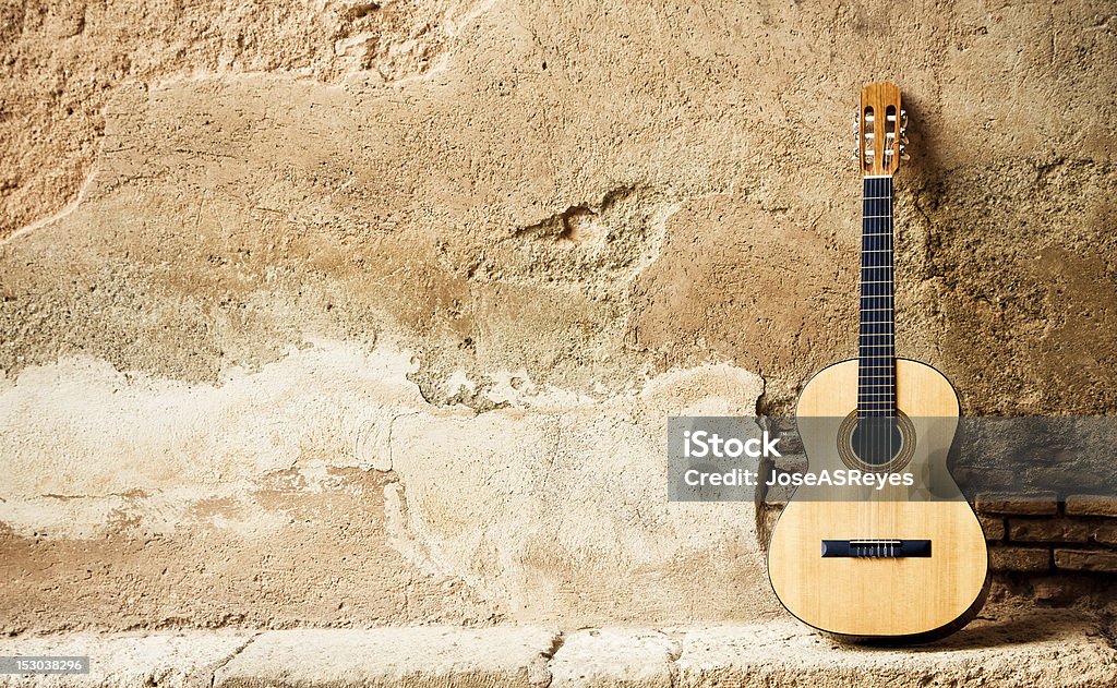 Spanish guitarr on wall Spanish guitar on old wall, copy spaced. Acoustic Guitar Stock Photo