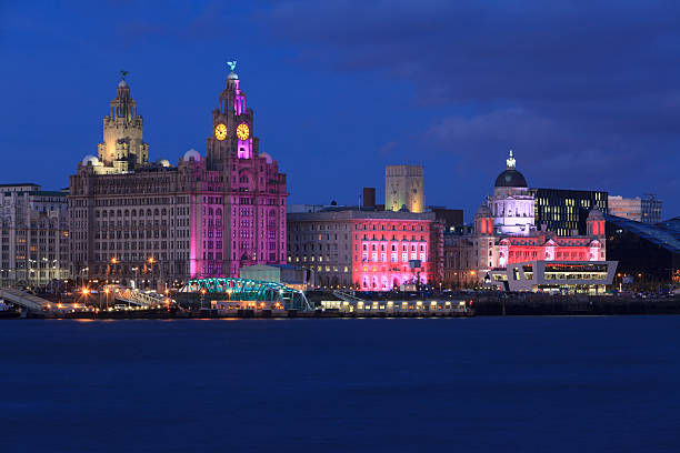 Liverpool Waterfront at Night Night view of  Liverpool Pier head showing the Three Graces. liverpool england stock pictures, royalty-free photos & images