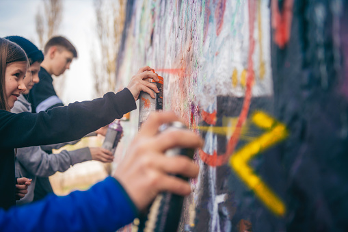 kids spraying graffiti on a wall in park in Berlin