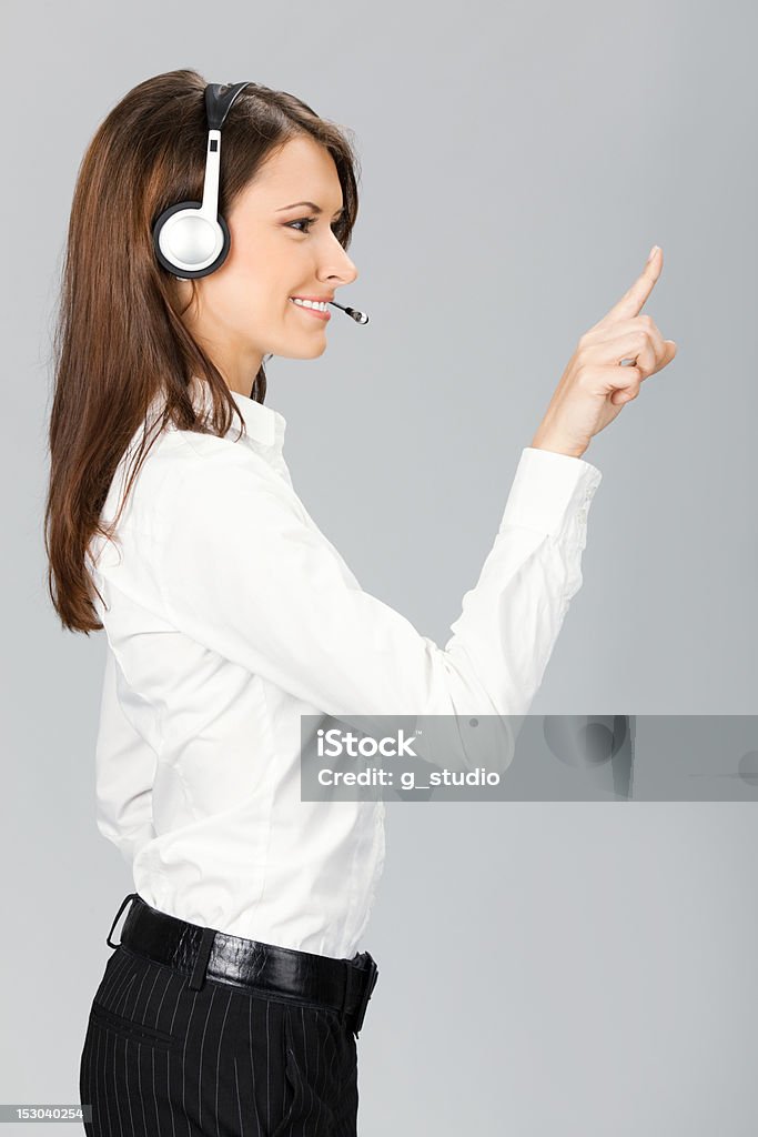 Soporte teléfono operador señalando, sobre gris - Foto de stock de Adulto libre de derechos