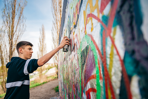 Lissabon, Portugal – October 25, 2018: A back view of a graffiti artist at work on a mural in Lisbon, Portugal