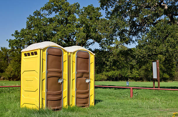 Two yellow portable toilets at a park Two yellow portable toilets at a park portable toilet stock pictures, royalty-free photos & images