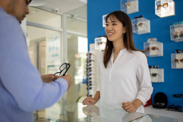Mid adult Japanese woman working in an eyewear store talking to a customer