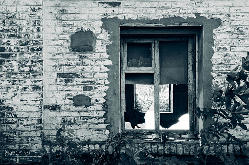 Abandoned brick building, window with wooden frame, glass broken, black and white photography