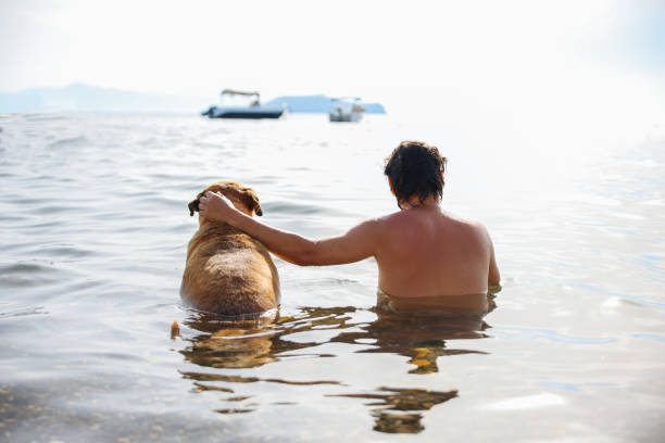 Handsome young man holding his dog at the beach