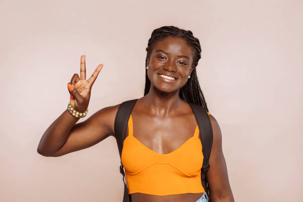 Young african female student gesturing peace victory sign with fingers