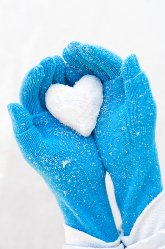 Heart of snow in blue mitten.