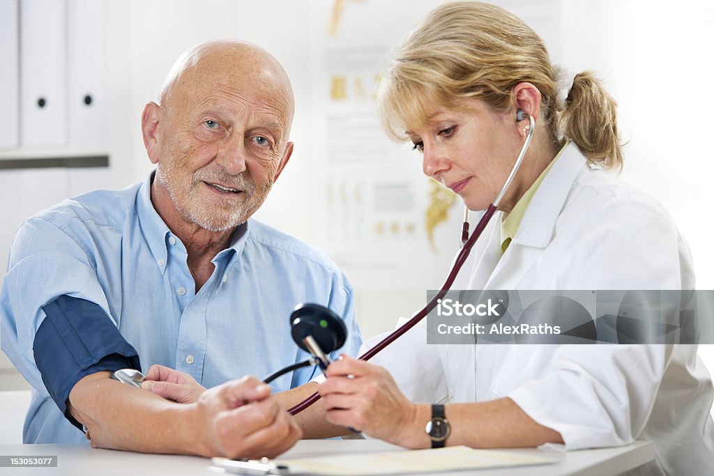 Medical exam Female doctor measuring blood pressure of senior  man 70-79 Years Stock Photo