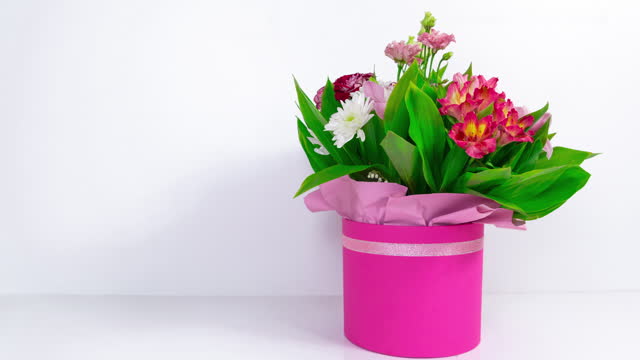Big beautiful bouquet of  various natural flowers in pink gift box to turn. White background.