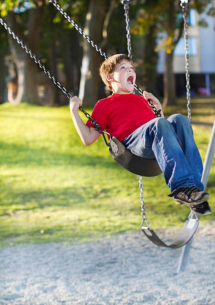Happy young boy playing on swing stock photo