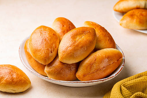 Pirozhki, piroshki. Homemade baked yeast leavened boat shaped buns with braised cabbage fillings. Pirozhki are a popular street food and comfort food in Eastern Europe.