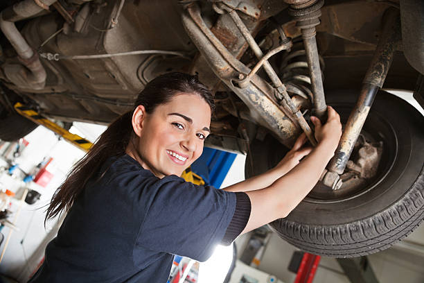 Portrait of smiling young female mechanic Portrait of smiling young female mechanic inspecting a CV joing on a car in auto repair shop shock absorber stock pictures, royalty-free photos & images