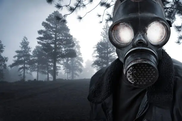 An unnerving creature stares at the viewer through the glowing eyes of a gas mask.