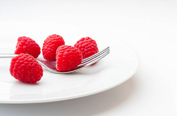 Ripe raspberries on a plate with fork