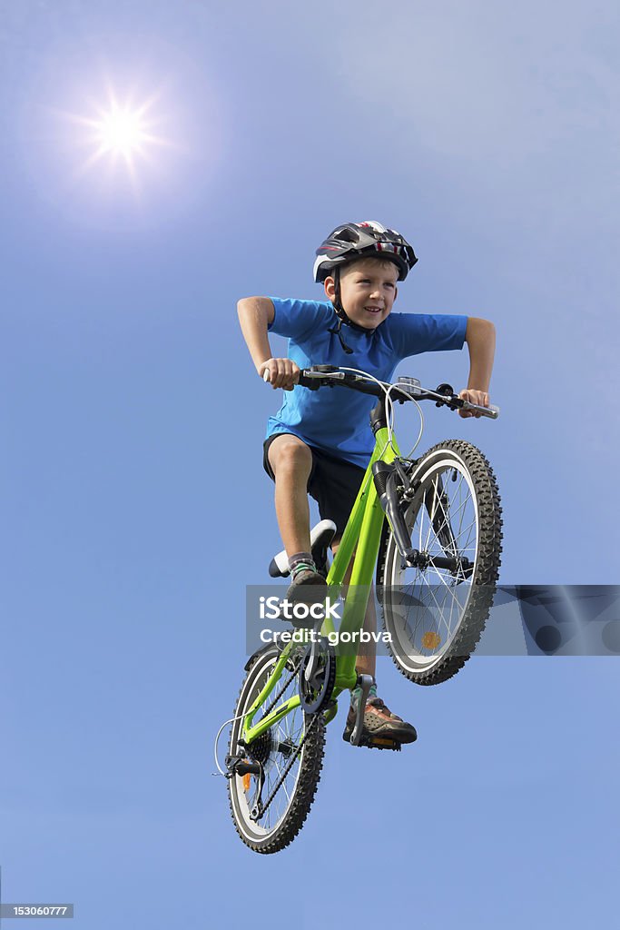 Giovane ragazzo saltare su una bicicletta sotto il sole - Foto stock royalty-free di Bambino