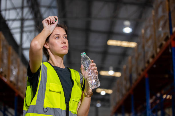 Women engineer drinking water from plastic bottle after working at factory during break. Drinking pure water refreshes body. Image female drinking water for advertise.