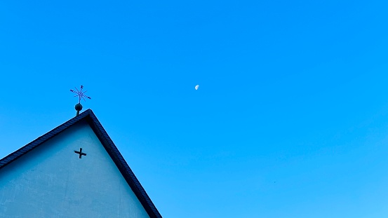 Church top and moon in the morning on blue sky