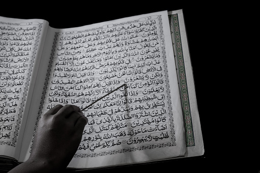 A Muslim is reading the Koran or reciting the Koran, let's read the Koran.