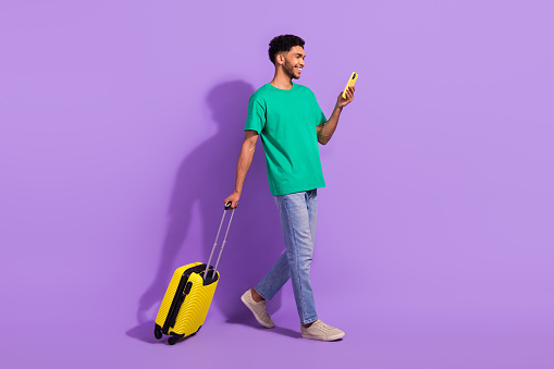 Full length profile portrait of handsome person use smart phone walking isolated on purple color background.