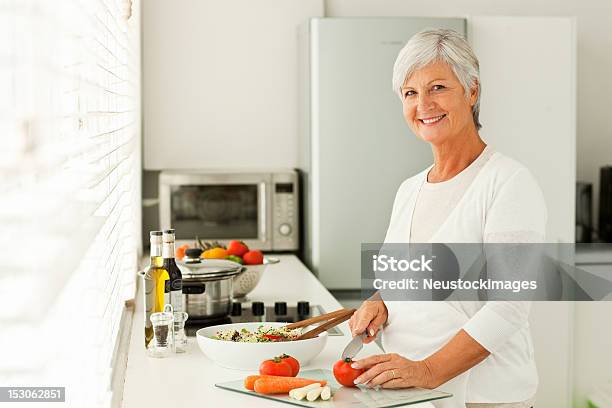 Улыбается Старший Женщина Резки Овощей В Кухне — стоковые фотографии и другие картинки 60-64 года - 60-64 года, Женщины, Портрет