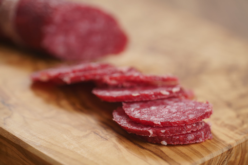 sliced thin salami sausage on cutting board, wide photo