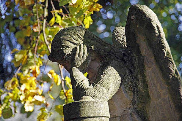 Sad mourning woman with cloud background; a cemetery statue against blue sky.