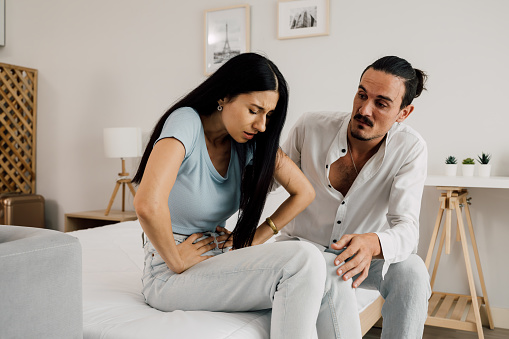 Young wife with health problem at home, Husband taking care of wife during sick, Man comforting wife while her having stomachache, People with illness at home. High quality photo