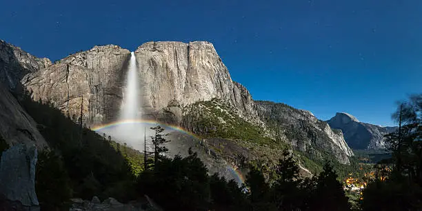 Moonbow forms in the mist at the base of Upper Yosemite Fall at about 2AM during a supermoon.  Half Dome and Yosemite Village are visible on the right. This very wide angle image was created using four exposures stitched together.  Yosemite National Park, California, 2012.  Brian Hawkins Photography http://www.brianhawkinsphotography.com