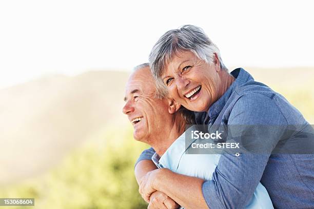 Sonriendo Par Abrazar Al Aire Libre Foto de stock y más banco de imágenes de 60-69 años - 60-69 años, Abrazar, Adulto