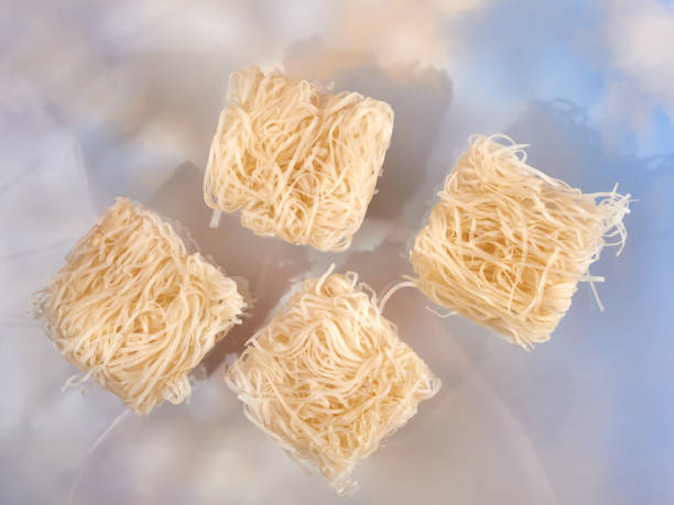 Rice noodles for Pad Thai, uncooked (raw), on blue background, dramatic lighting. stock photo