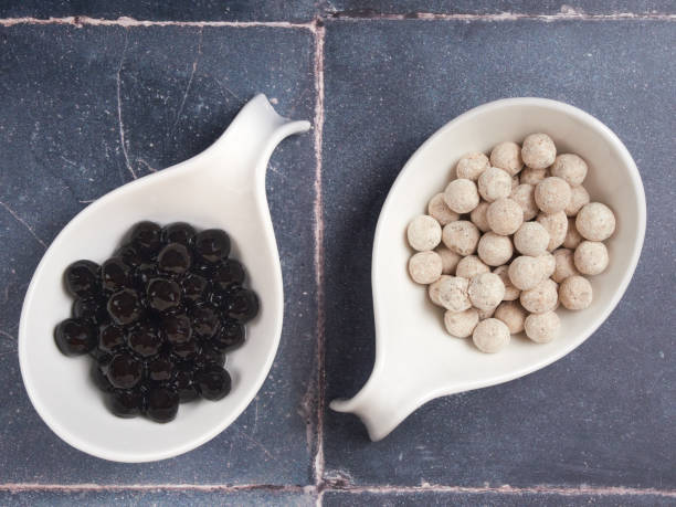 Raw and cooked tapioca pearls on gray tile background stock photo