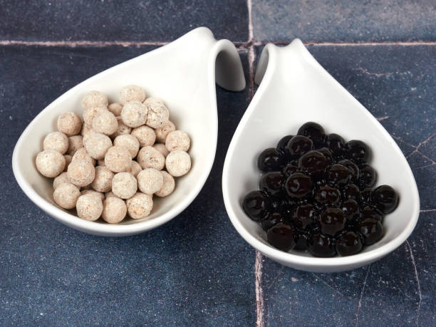 Raw and cooked tapioca pearls on gray tile background stock photo