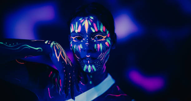 istock Young Dancer with Glowing Body Art Paint and White Clothes Creates Magic with Contemporary Dance Solo Routine. Choreographer Performs a Modern Dance Show on a Dark Stage 1530709533