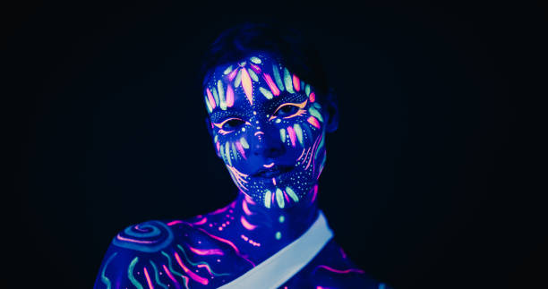 istock Young Sensual Model Poses with Grace and Poise, Her Vivid Body Paint Complementing Dark Abstract Background and Distorted Mirror Image, Resulting in a Radiant Fashionable Beauty Photo 1530709544