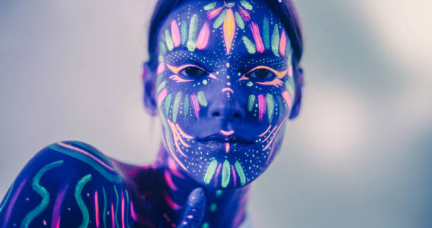 istock Young Sensual Model Poses with Grace and Poise, Her Vivid Body Paint Complementing Dark Abstract Background and Distorted Mirror Image, Resulting in a Radiant Fashionable Beauty Photo 1530715343