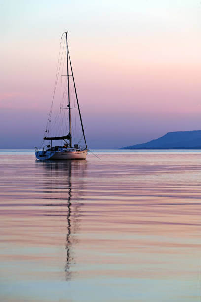 One sailing boat on lake Balaton at twilight in tall format